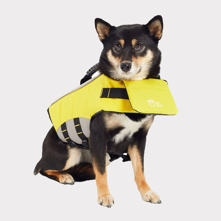 Black and tan dog wearing a yellow GF Pet dog flotation device with reflective straps and sturdy handle